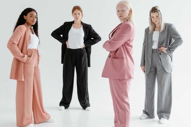 Four diverse women in stylish business suits exuding confidence and strength in a studio setting.