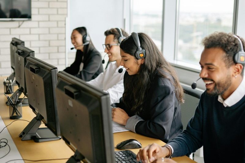 A diverse group of call center employees working together at desks in a modern office.