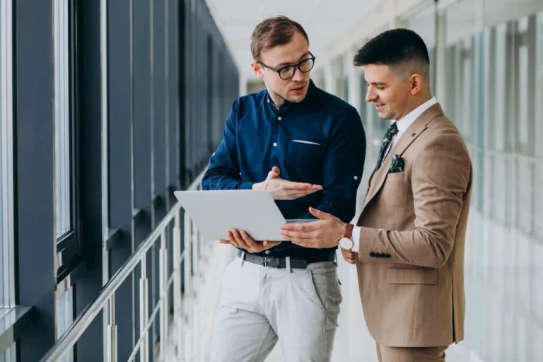 two-male-colleagues-office-standing-with-laptop-